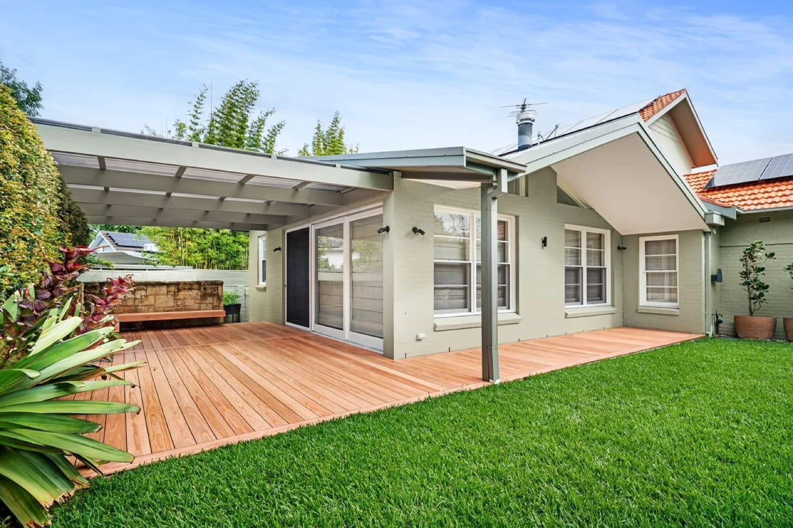 Deck wrapping cottage under roofed patio, lawn